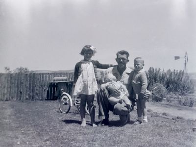 Hendrik Lodewyk Malherbe "Hennie" Oosthuizen (1909-1979) kneeling on the grass with three of his children: FRANCES...
