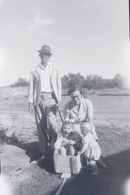 Hennie Oosthuizen in a hat and dark glasses pulling a home-made box cart with a small girl sitting in it, laughing;...