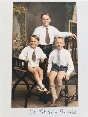 The three Marincowitz brothers in a photographer's studio, all in white shirts and ties. TOKKIE stands behind in...