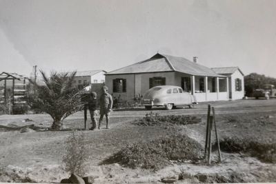 The homestead at Vischat: a low gabled house with a corrugated-iron roof and a verandah on two sides, outbuildings...