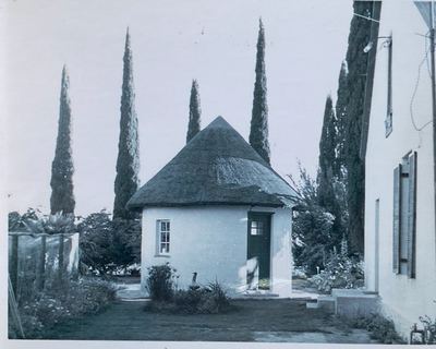 THE RONDAWEL ITSELF, close to: a round whitewashed building with a conical thatched roof, a dark door and one small...
