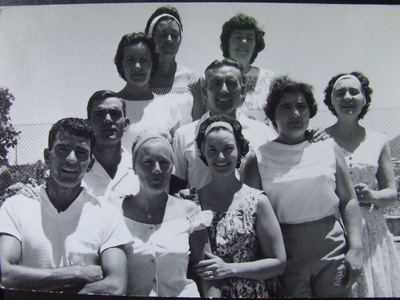 Ten grown brothers and sisters crowded together in the sun against a wire fence, the eldest at the back. FRANS...