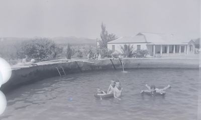 Four boys swimming in the farm dam at Vischat, three of them holding on to a tractor-tyre tube and one floating on...