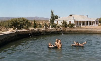 Four boys swimming in the farm dam at Vischat, three of them holding on to a tractor-tyre tube and one floating on...