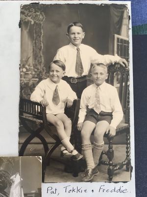 The three Marincowitz brothers in a photographer's studio, all in white shirts and ties. TOKKIE stands behind in...
